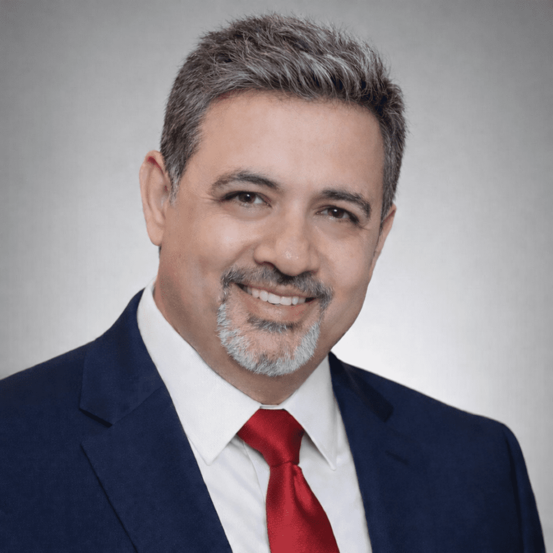 Man in suit with gray hair smiling.