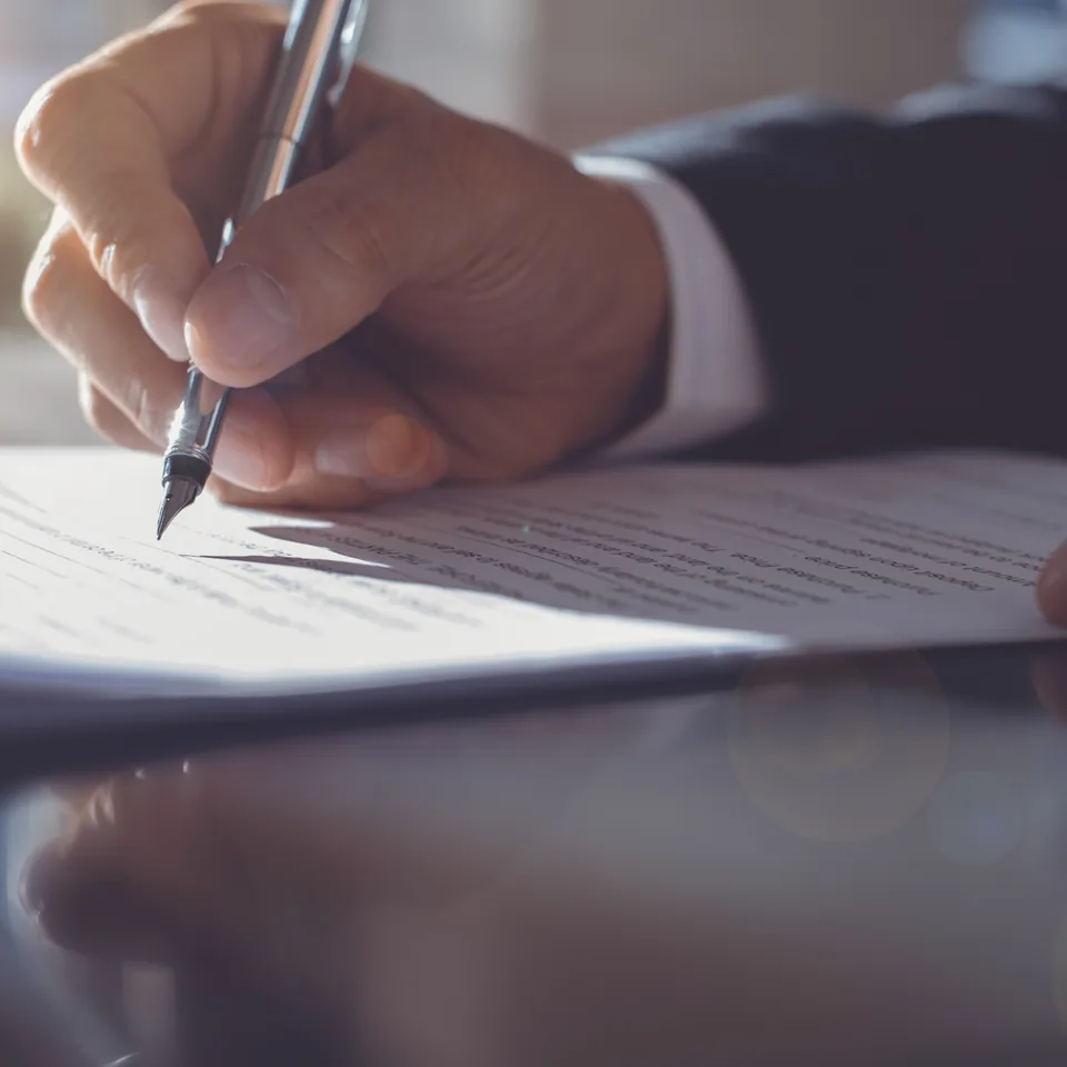 A person signing a document with a pen